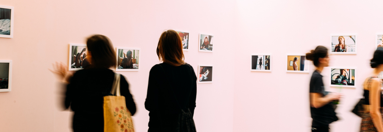 Visitors look at photography on exhibition wall.