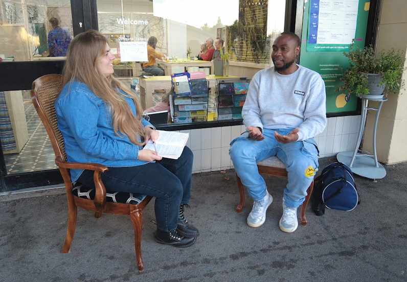 Holly and Rungano sit outside the Community Wellbeing Space.