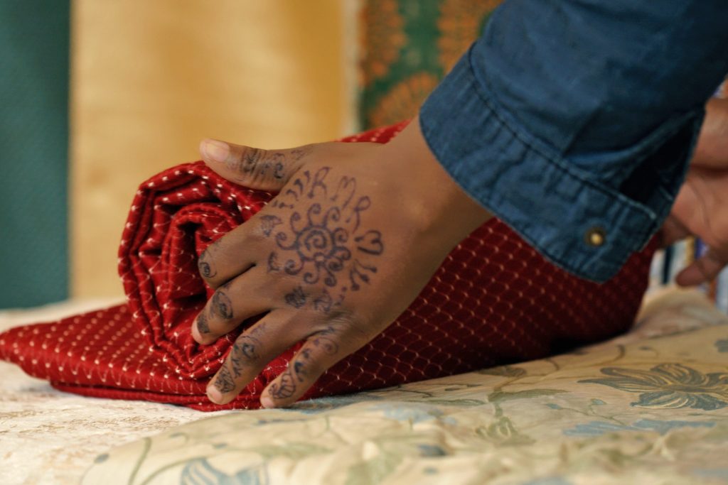 Hands roll up fabric on table.